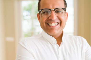 Evde kameraya gülümseyen gözlük takan orta yaş erkek