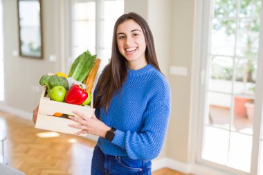 Genç kadın teslim bakkaliye ahşap bir kutu tutarak gülümsüyor