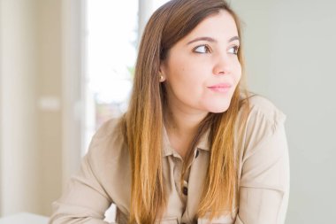 Güzel genç kadın evde doğal yüz emin gülümseme ile pozuyla profil rahatla tarafına, seyir.