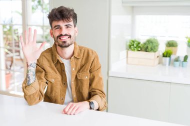 Beyaz masada oturan rahat ceket giyen genç adam gösteren ve parmak numarası beş ile işaret kadar güven ve mutlu gülümseyen.