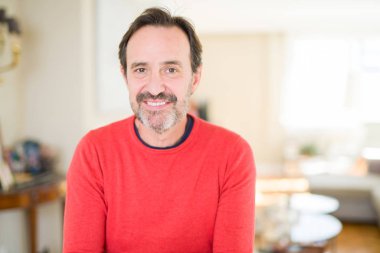 Evde kameraya bakarak gülümseyen yakışıklı orta yaş erkek