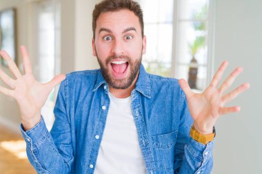 Yakışıklı adam evde deli ve başarı için hayran kaldırdı Kollarını açarak kutluyor ve heyecanlı çığlık gözleri açık. Kazanan kavramı