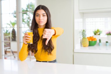 Genç kadın öfkeli yüzü ile taze portakal suyu bir bardak içme, negatif işareti başparmak aşağı ile sevmediğim gösteren, ret kavramı