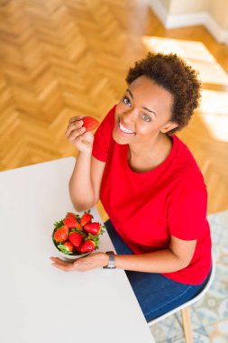 Güzel genç Afro-Amerikan kadın taze kırmızı strawber yeme