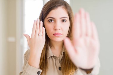 Nişan yüzüğü yandan açık eliyle dur işareti ile ciddi ve kendine güvenen ifade, savunma hareketi yaparken gösterilen güzel genç kadın