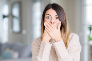 Evde kış kazak giyen genç güzel kadın kapsayan ağız elle hata için şok. Gizli kavramı.