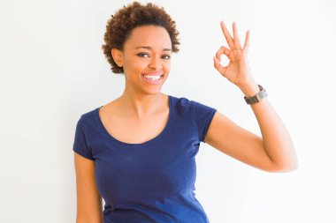Beyaz arka plan gülümseyen üzerinde genç güzel Afrikalı-Amerikalı kadın el ve parmaklar ok işaretiyle yapıyor olumlu. Başarılı ifade.