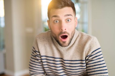 Genç yakışıklı adam evde korkuyor şok sürpriz yüz, korkuyor ve heyecanlı korku ifadesi ile