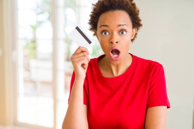 Kredi kartı bir sürpriz yüz, korkuyor ve heyecanlı korku ifadesi ile şok korkmuş tutan genç Afro-Amerikan kadın