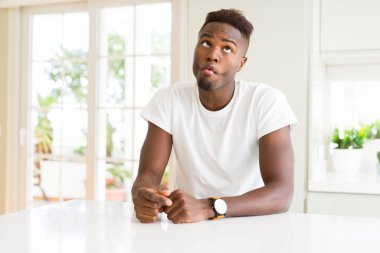 Evde beyaz masada yakışıklı Afrikalı Amerikan adam dudaklar, çılgın ve komik jest ile balık yüzü yapma. Komik ifade.