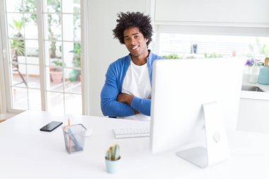 Afrika kökenli Amerikalı adam bilgisayar mutlu yüz ile gülümseyen kullanarak çalışma silah kameraya bakarak geçti. Olumlu bir kişi.