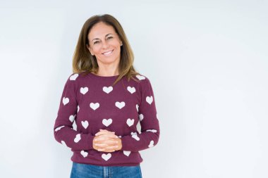 Arka plan eller üzerinde kalp kazak giyen güzel orta yaş kadın birlikte izole ve rahat ve neşeli gülümseyen parmak çarpı işareti. Başarı ve iyimser