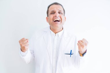 Orta yaş doktor adam beyaz arka plan kutlama üzerinde tıbbi bir palto giyiyor şaşırttı ve başarı için kaldırdı Kollarını açarak hayret ve gözleri açık. Kazanan kavramı.