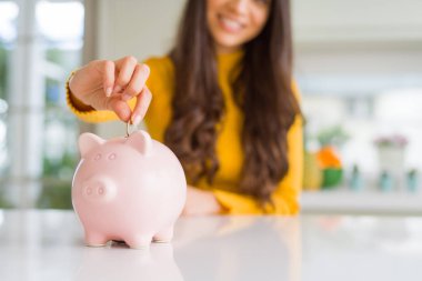 Yatırım olarak Piggy banka içinde bir sikke koyarak gülümseyen kadın yakın