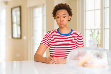 Genç güzel Afrikalı-Amerikalı kadın evde komik surat ile yanakları şişirme. Ağız ile hava, deli ifade şişirilmiş.