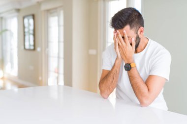 Yakışıklı İspanyol adam rahat beyaz t-shirt evde üzgün ifade ile yüz elleri ile kapsayan ağlıyor. Depresyon konsepti.