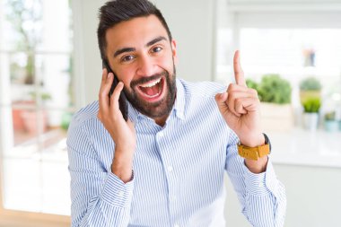 Akıllı Telefonda konuşan yakışıklı İspanyol iş adamı bir fikir veya soru mutlu yüz, bir numara ile parmak işaret ile şaşırdı