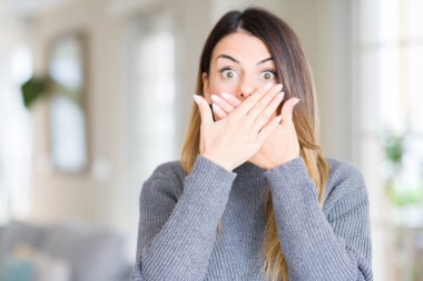 Evde kış kazak giyen genç güzel kadın kapsayan ağız elle hata için şok. Gizli kavramı.