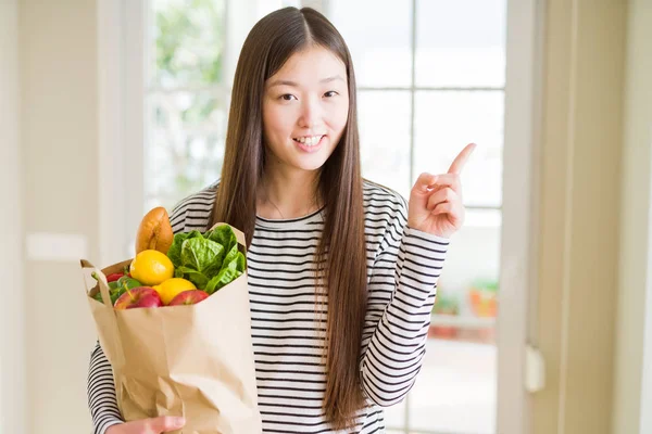 Vacker Asiatisk Kvinna Håller Papperspåse Färska Matvaror Mycket Glad Pekar — Stockfoto