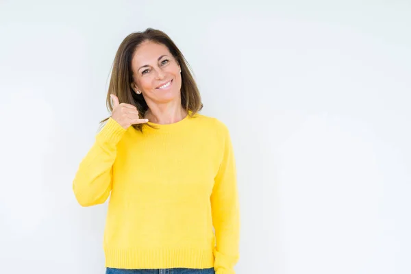孤独な背景の上に黄色いセーターを着ている美しい中年の女性電話で話すように手と指で電話ジェスチャーをして笑顔 概念の伝達 — ストック写真