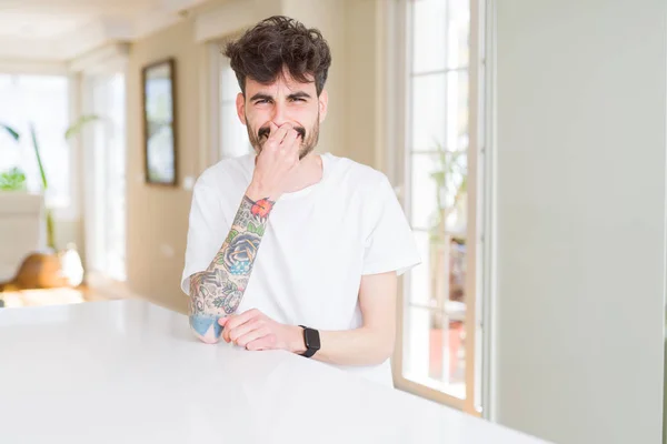 Hombre Joven Con Camiseta Casual Sentado Mesa Blanca Oliendo Algo —  Fotos de Stock