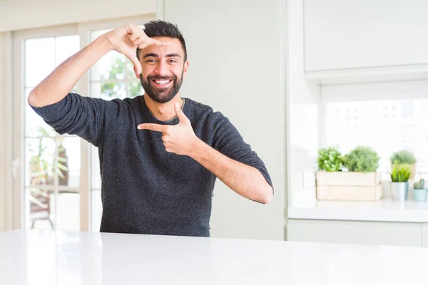 ハンサムなヒスパニック系の男性は 笑顔で手と指で家庭の笑いを作るフレームでカジュアルなセーターを着ています 創造性と写真のコンセプト — ストック写真