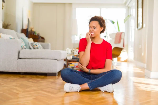 年轻美丽的非洲裔美国妇女坐在地板上 在家里显得紧张和紧张的手在嘴咬指甲 焦虑问题 — 图库照片