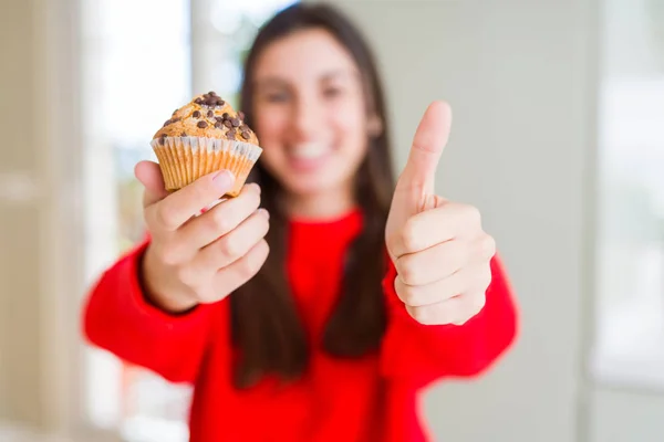 チョコレートチップスを食べている美しい若い女性は 大きな笑顔で満足しています サインをして 指で親指を 優れた兆候 — ストック写真