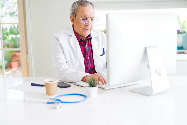 Człowiek starszy lekarz w klinice koncentruje pracę z komput — Zdjęcie stockowe