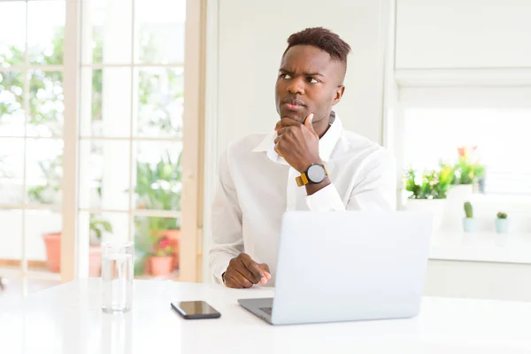 アフリカ系アメリカ人のビジネスマンは 手を使ってノートパソコンを使用して作業する質問 物思い表現を考えています 思慮深い顔をして微笑む ダウトコンセプト — ストック写真