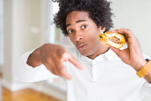 非洲裔美国人饥饿的男子吃汉堡包吃午饭用手指指着镜头 手的标志 积极和自信的手势从前面 — 图库照片