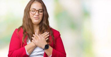 Artı boyutu genç iş kadını zarif ceket ve gözlük izole arka plan üzerinde giyen güzel ile gülümseyen gözlerin kapalı ve yüzünde minnettar jest ile göğüs üzerinde eller. Sağlık kavramı.