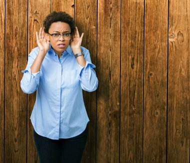 Genç güzel Afro-Amerikan iş kadını iki eliyle kulak jest, dedikodu için meraklı üzerinde dinliyoruz izole arka plan üzerinde. İşitme sorunu, sağır