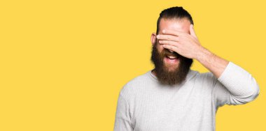 Genç sarışın adam rahat kazak gülümseyen ve gözler için sürpriz kapsayan yüz el ile gülüyor. Kör kavramı.