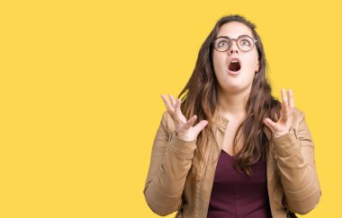 Güzel artı boyutu genç kadın izole arka plan üzerinde bir elbise ve deri ceket giyiyor çılgın ve deli çığlık ve agresif ifade ve silah ile bağırdı kaldırdı. Hayal kırıklığı kavramı.