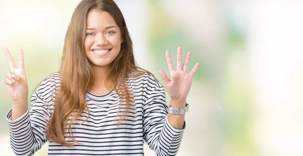 年轻美丽的黑发女人穿着条纹毛衣在孤立的背景显示和手指指向数字 同时微笑着自信和快乐 — 图库照片