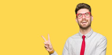 Mutlu yüz zafer işareti yaparken kameraya göz kırpıyor ile gülümseyen gözlüklü genç yakışıklı iş adamı. İki numaralı.