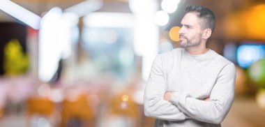 İkna ve kendine güvenen tarafına silahlarla seyir gülümseyen izole arka plan üzerinde sweatshirt giyen genç yakışıklı adam geçti