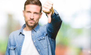 Mavi gözler ve sakal giyen denim ceket ile yakışıklı adam mutsuz ve öfkeli gösteren reddetme ve başparmak aşağı jest ile negatif bakıyor. Kötü ifade.