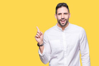 Kameraya bakarak yan el ve parmak ile işaret eden genç iş adamı yüzünde kocaman bir gülümseme ile izole arka plan üzerinde.