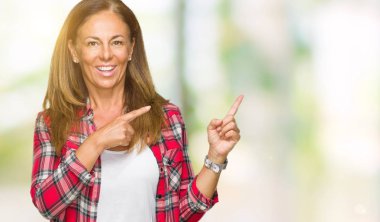 Orta yaş yetişkin kadın gülümseyerek ve iki elleri ve parmakları ile tarafına işaret kamera bakarak izole arka plan üzerinde rahat gömlek giymiş.