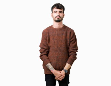 Üzerinde kış kazak giyen genç yakışıklı adam arka plan gevşek yüzünde ciddi bir ifade ile izole. Basit ve doğal kameraya bakıyor.