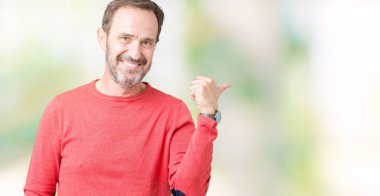 Mutlu yüz görünümlü ve başparmak yukarı ile yan işaret ile gülümseyen izole arka plan üzerinde kış kazak giyen yakışıklı Orta Çağ ağarmış kıdemli adam.