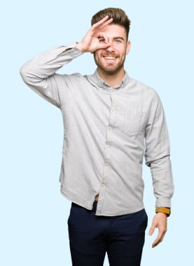 Genç ve yakışıklı bir adam günlük gömleğini giyiyor. El hareketleriyle gülümsüyor, gözleriyle mutlu yüzüyle parmaklarının arasından bakıyor..