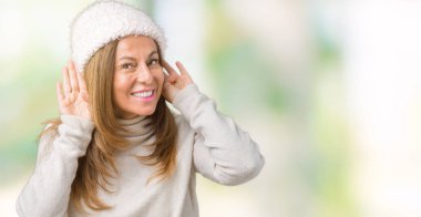 Her iki kulak jest, dedikodu için meraklı ellerde dinliyoruz izole arka plan üzerinde kış kazak ve şapka giyen güzel orta yaş kadın. İşitme sorunu, sağır