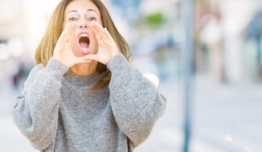 İzole arka plan ağzına sesle elleriyle kızgın bağırarak üzerinde kış kazak giyen güzel orta yaş kadın