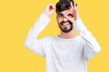 Yakışıklı delikanlı gülümseyen, parmakları ile mutlu yüz üzerinden seyir göz el ile ok jest yapıyor izole arka plan üzerinde güneş gözlüğü takıyor.