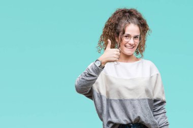 Güzel esmer kıvırcık saçlı Genç kız mutlu yaşasın el ile jest yapıyor izole arka plan üzerinde gözlük takıyorum. Kameraya bakarak başarı gösteren ile ifade onaylama.