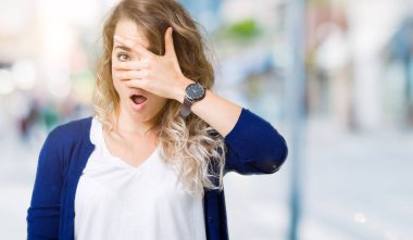 Yüz ve gözler el ile kapsayan şok bakmak izole arka plan üzerinde güzel genç sarışın kadın mahcup ifadeyle parmaklarımın arasından arıyorsunuz.