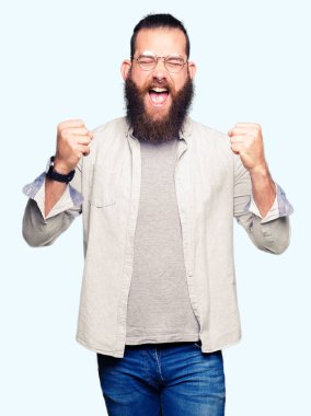 Silah ile başarı için heyecanlı gözlüklü genç sarışın adam zafer kutluyor gülümseyen kaldırdı. Kazanan kavramı.